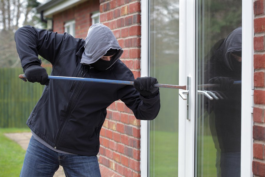 Burglar breaking into a house window with a crowbar